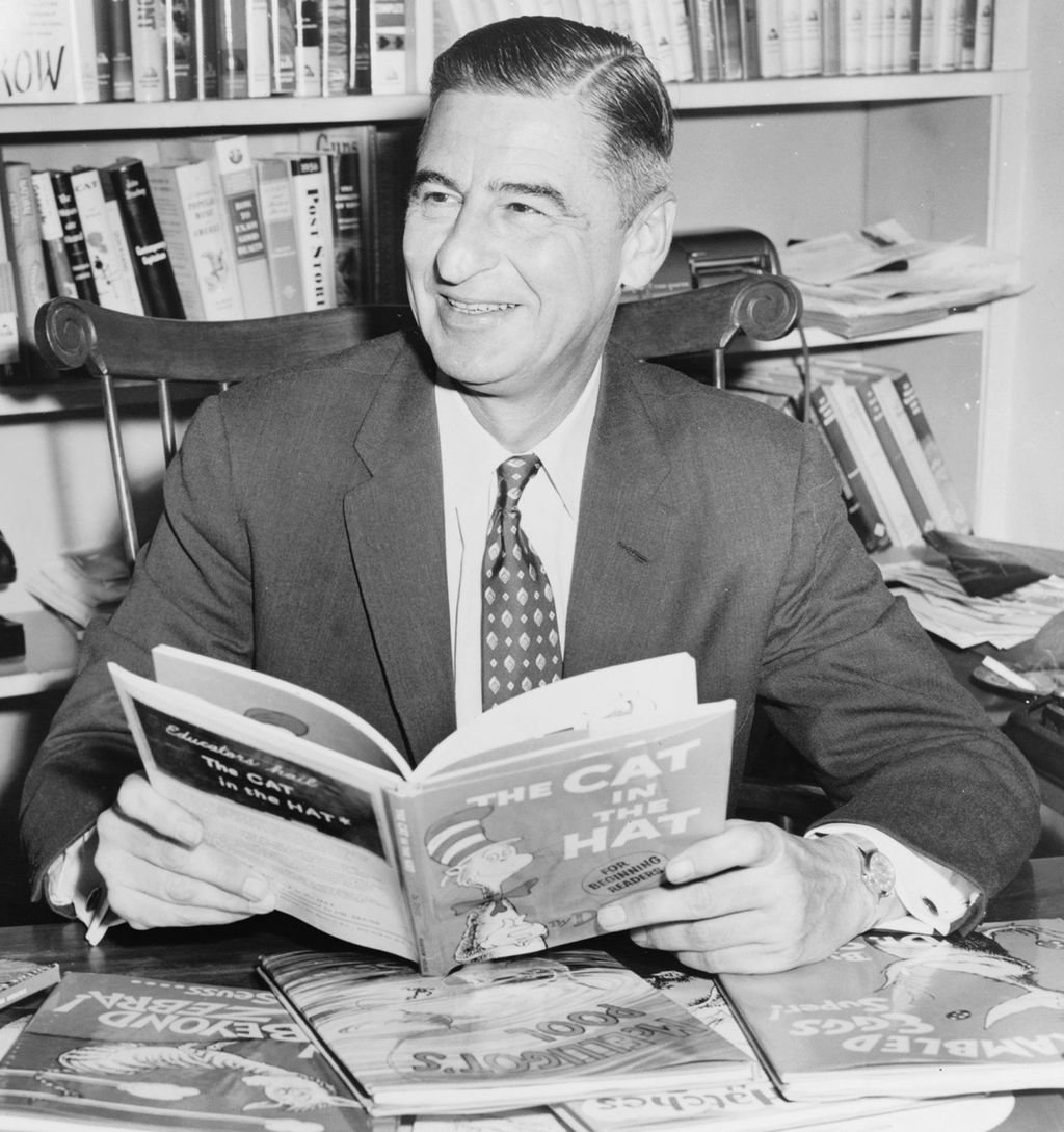 old photo of Dr. Suess holding the book he wrote entitle "The Cat In the Hat"